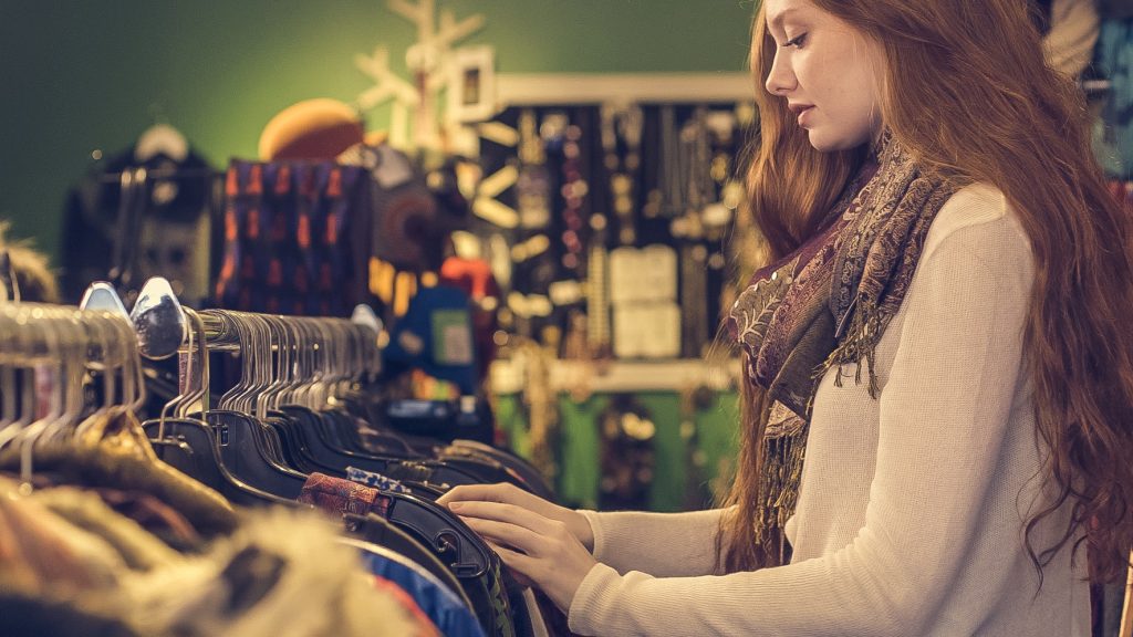 a lady in a store looking through a clothes rack