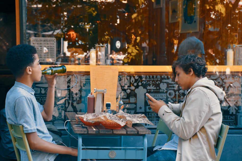 two boys eating food outside of a restaurant