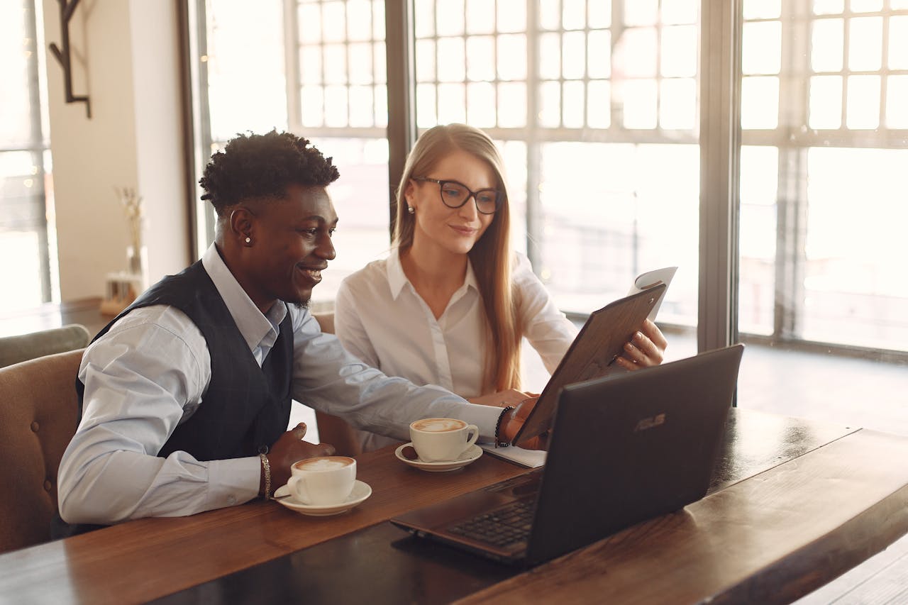 two people sat in a coffee shop using a laptop