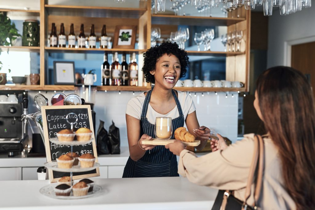 a cafe worker taking a payment for coffee from a customer