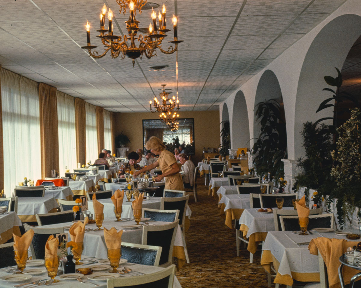 A luxurious dining room with many round tables and a large window.